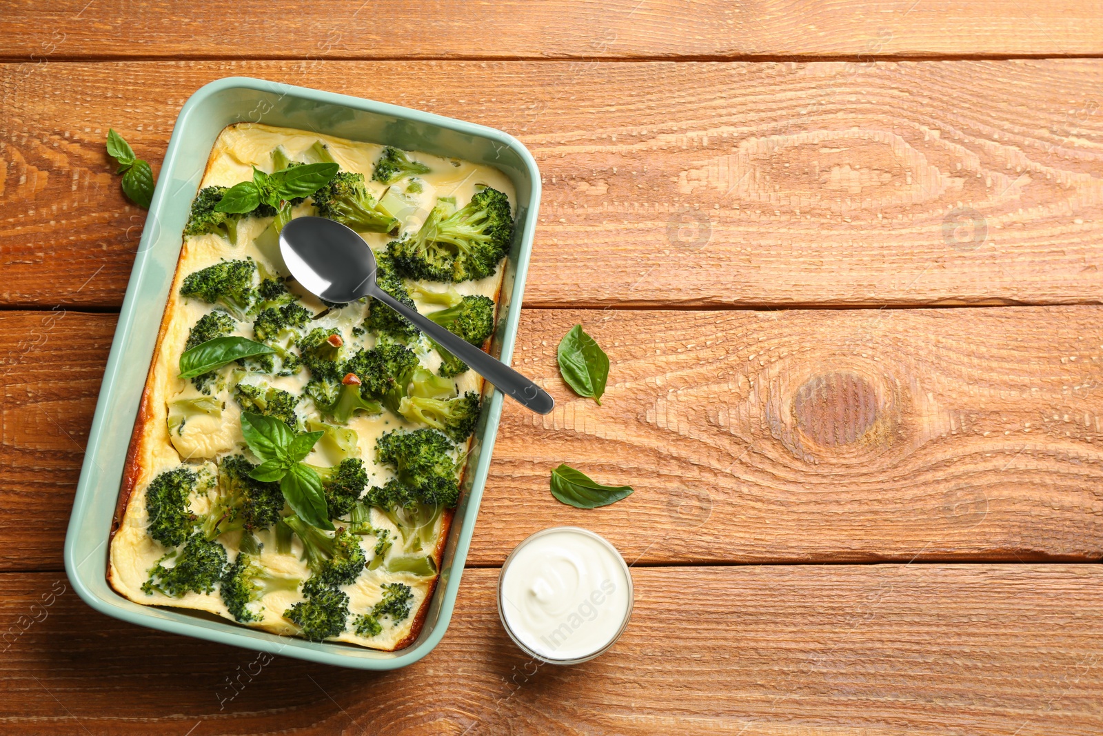 Photo of Tasty broccoli casserole in baking dish on wooden table, flat lay. Space for text