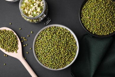 Different dishware with green mung beans on black background, flat lay