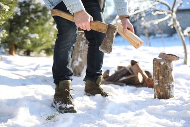 Man chopping wood with axe outdoors on winter day, closeup