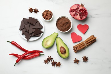 Photo of Natural aphrodisiac. Different products and paper hearts on white marble table, flat lay