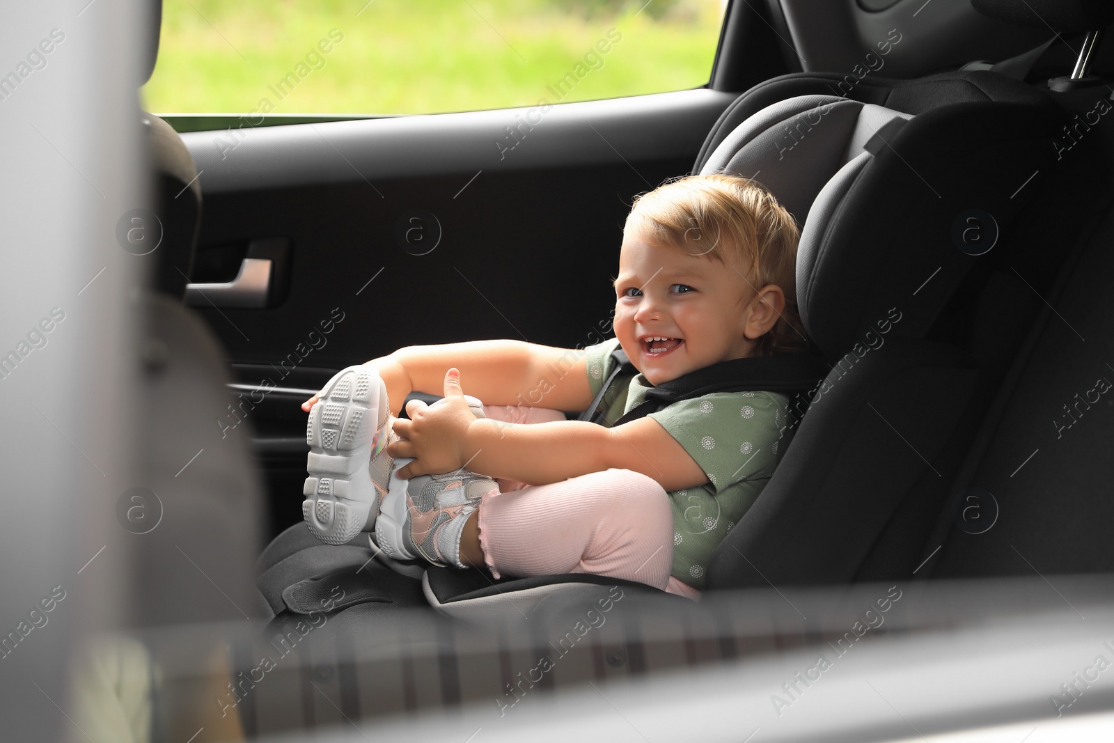 Photo of Cute little girl sitting in child safety seat inside car