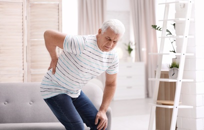 Senior man suffering from back pain at home