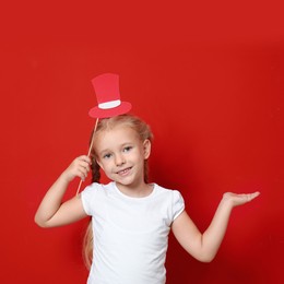 Cute little girl with red hat prop on red background. Christmas celebration