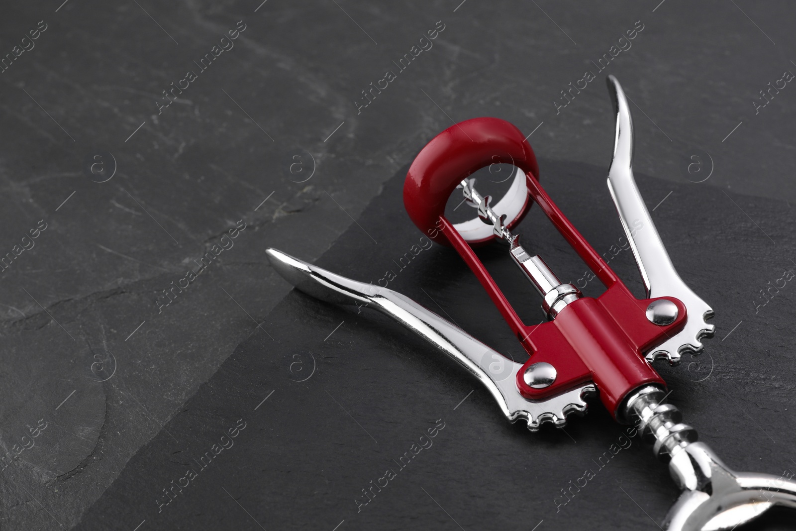 Photo of One wing corkscrew on grey textured table. Space for text