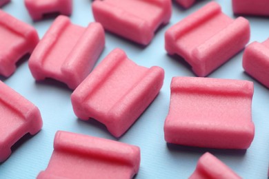 Photo of Tasty pink chewing gums on light blue background, closeup