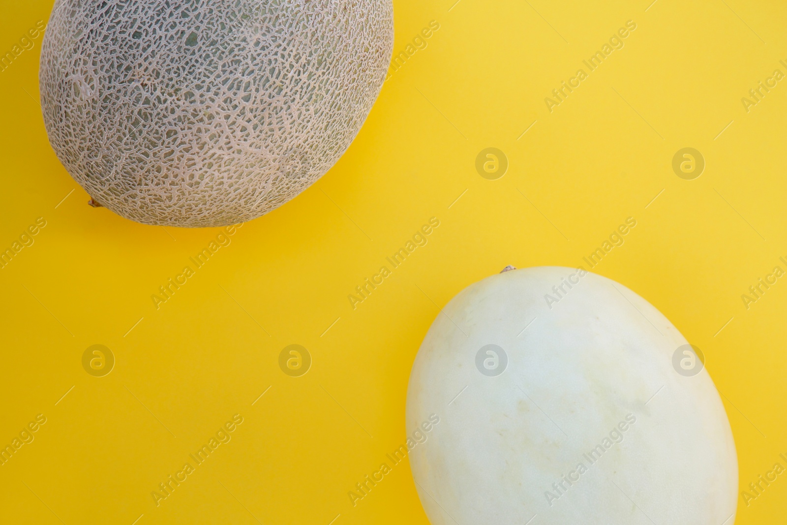 Photo of Different tasty ripe melons on yellow background, flat lay