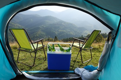 Photo of Chairs and cool box with bottles of beer in mountains, view from tent