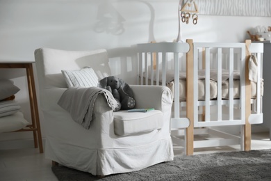 Photo of Baby room interior with crib and armchair. Idea for design