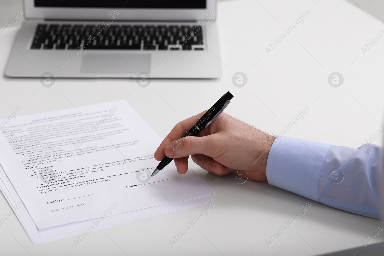 Photo of Businessman signing contract at white table, closeup of hands