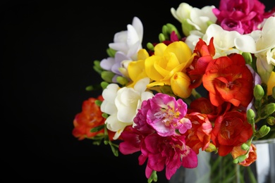 Bouquet of spring freesia flowers in vase on dark background, closeup. Space for text