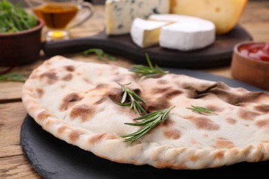 Photo of Delicious calzone and products on wooden table, closeup