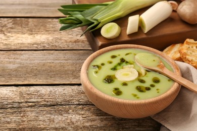 Delicious leek soup on wooden table, space for text