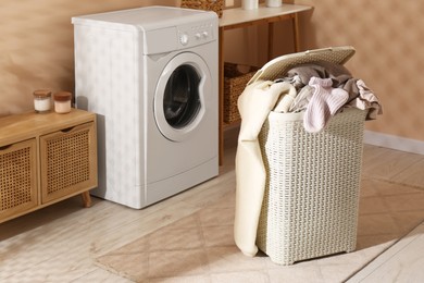 Laundry basket overfilled with clothes near washing machine in bathroom