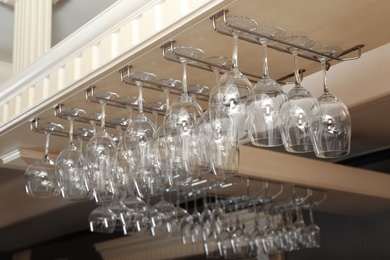 Photo of Set of empty clean glasses on bar racks