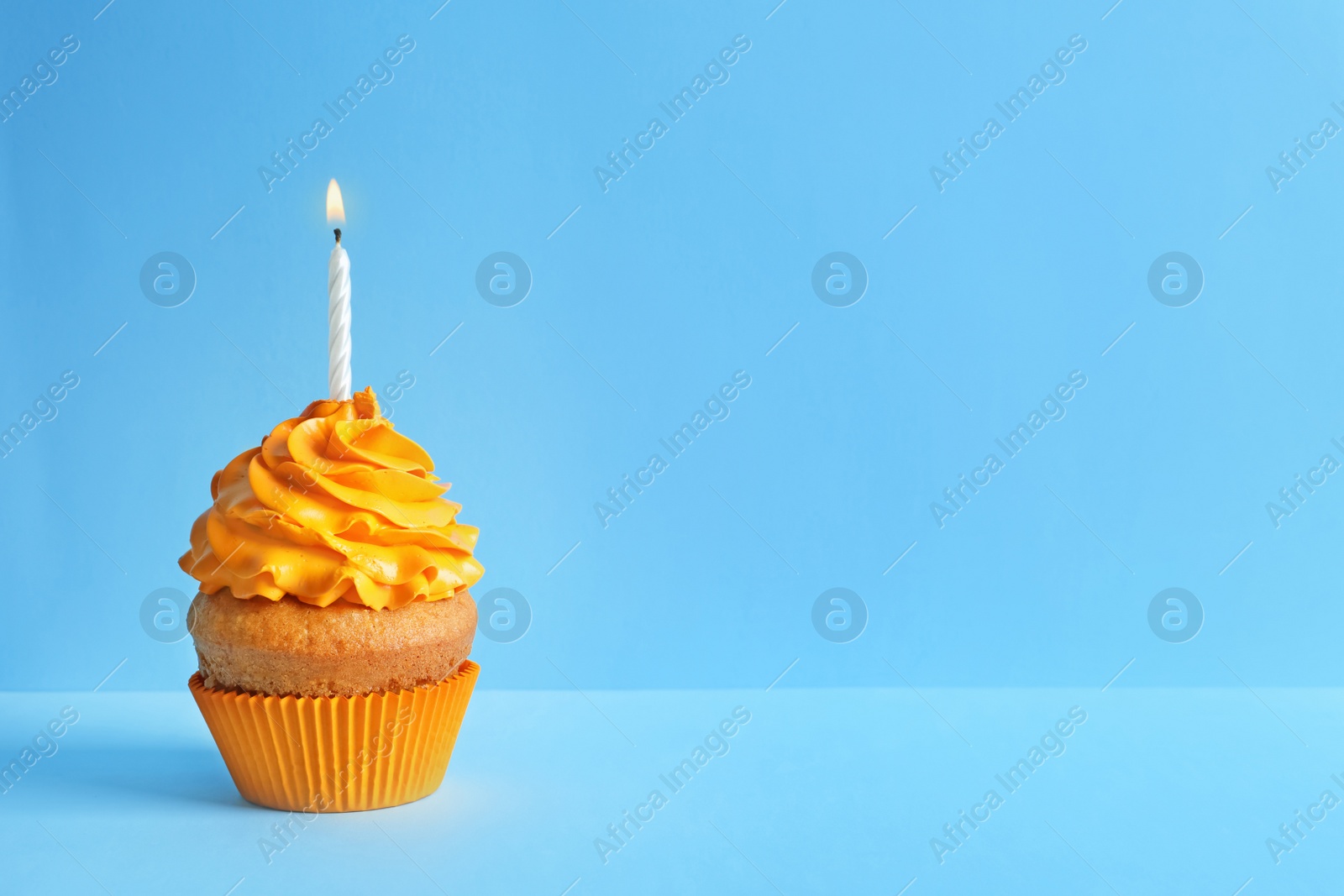 Photo of Delicious birthday cupcake with candle on color background