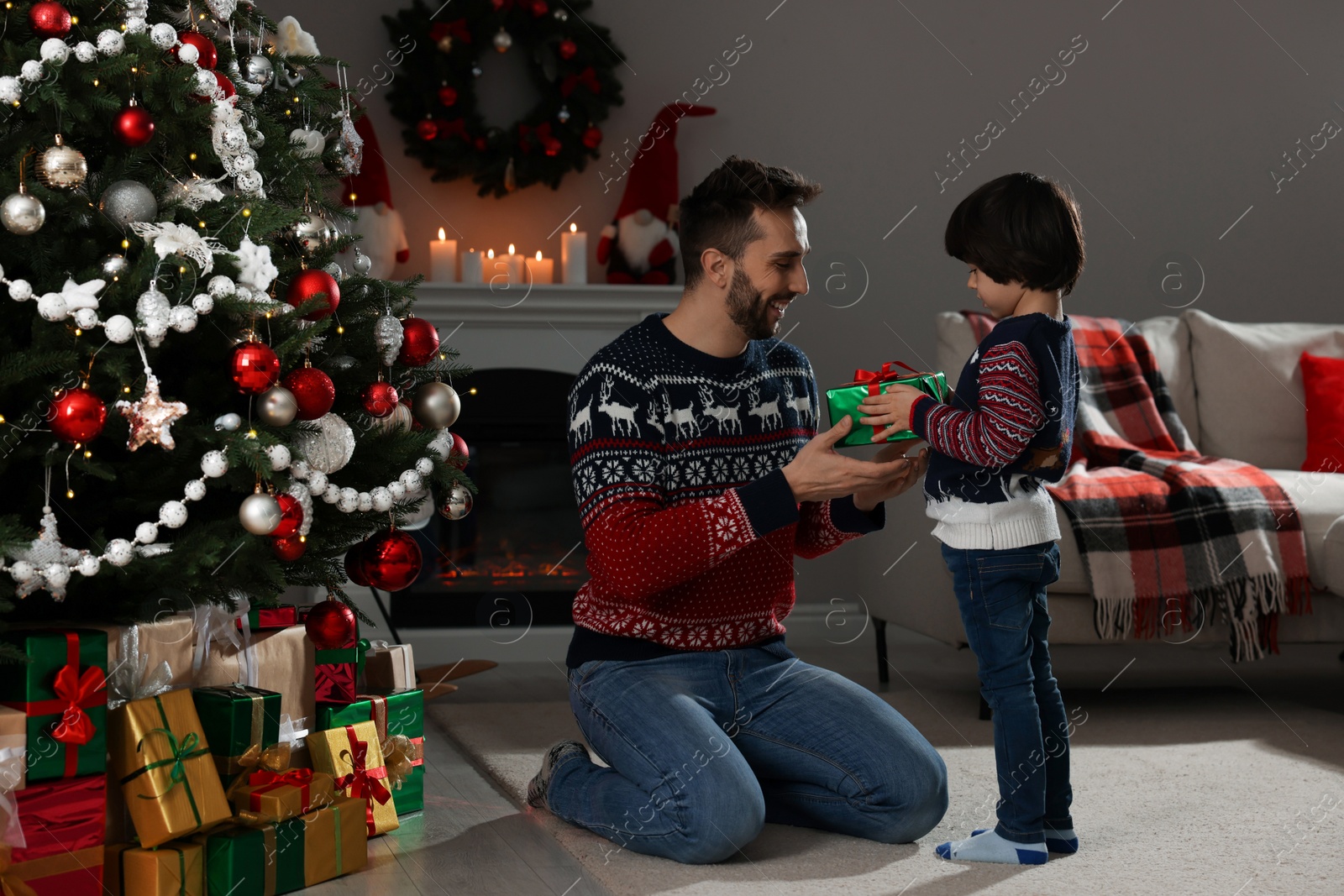 Photo of Cute son giving present to his father at home. Christmas celebration