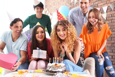 Young people celebrating birthday with tasty cake indoors