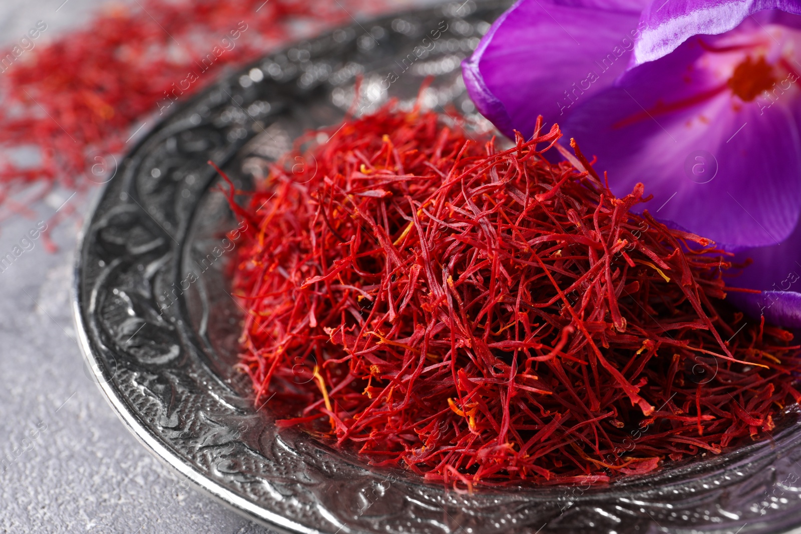 Photo of Dried saffron and crocus flower on grey table, closeup
