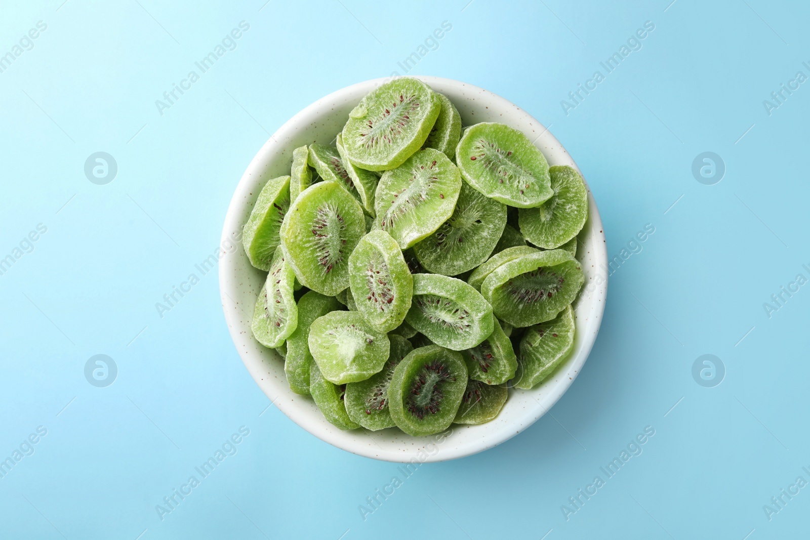 Photo of Bowl with slices of kiwi on color background, top view. Dried fruit as healthy food