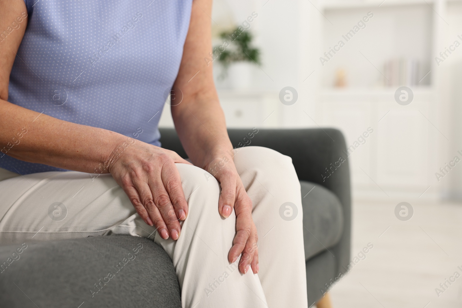 Photo of Arthritis symptoms. Woman suffering from pain in knee at home, closeup