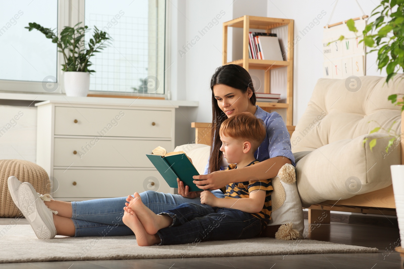 Photo of Mother reading book with her son in living room at home