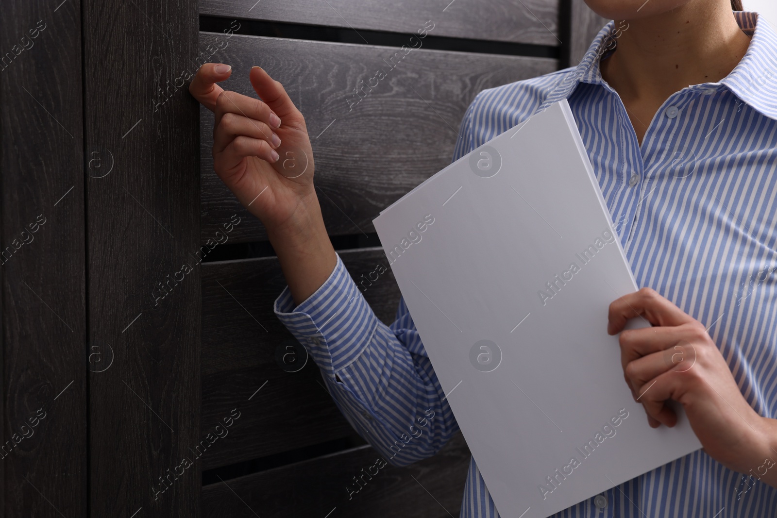 Photo of Collector with documents knocking on door indoors, closeup