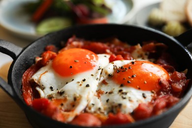 Photo of Tasty Shakshouka served in pan on table, closeup