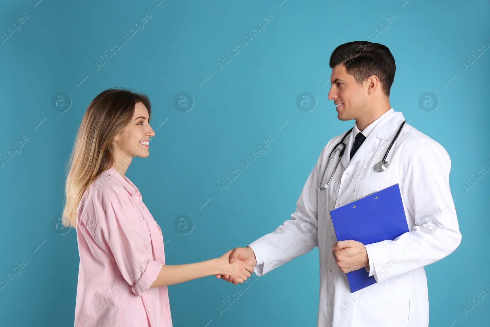 Photo of Doctor and patient shaking hands on light blue background