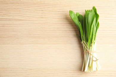 Photo of Bunch of wild garlic or ramson on wooden table, top view with space for text