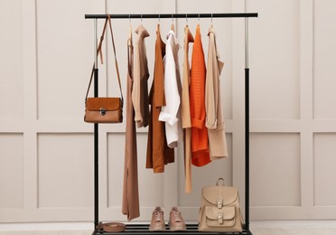 Photo of Rack with stylish women's clothes, shoes and accessories near light wall