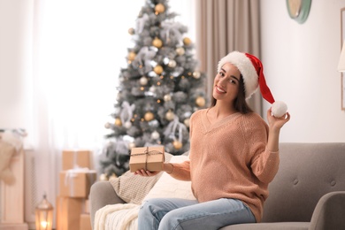 Happy pregnant woman with Christmas gift box at home. Expecting baby