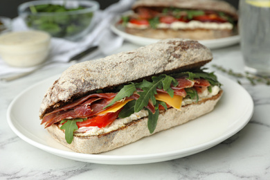 Photo of Delicious sandwich with fresh vegetables and prosciutto on white marble table