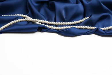 Photo of Beautiful pearls and dark blue silk on white background