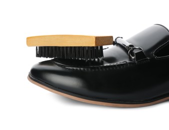Photo of Black shoe and brush on white background, closeup. Footwear care
