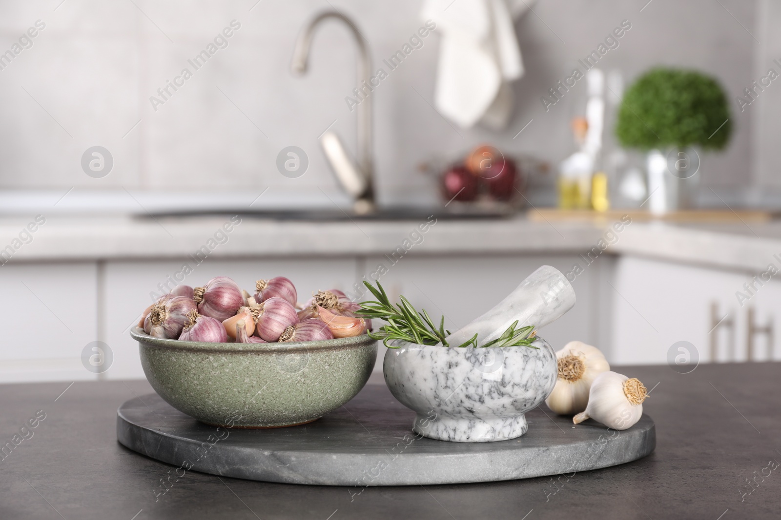 Photo of Fresh raw garlic and rosemary on grey table