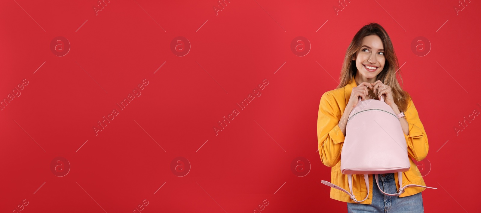 Photo of Happy woman with backpack on red background. Space for text