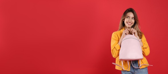 Happy woman with backpack on red background. Space for text
