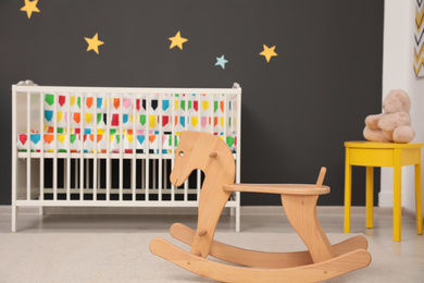 Cute baby room interior with modern crib and rocking horse