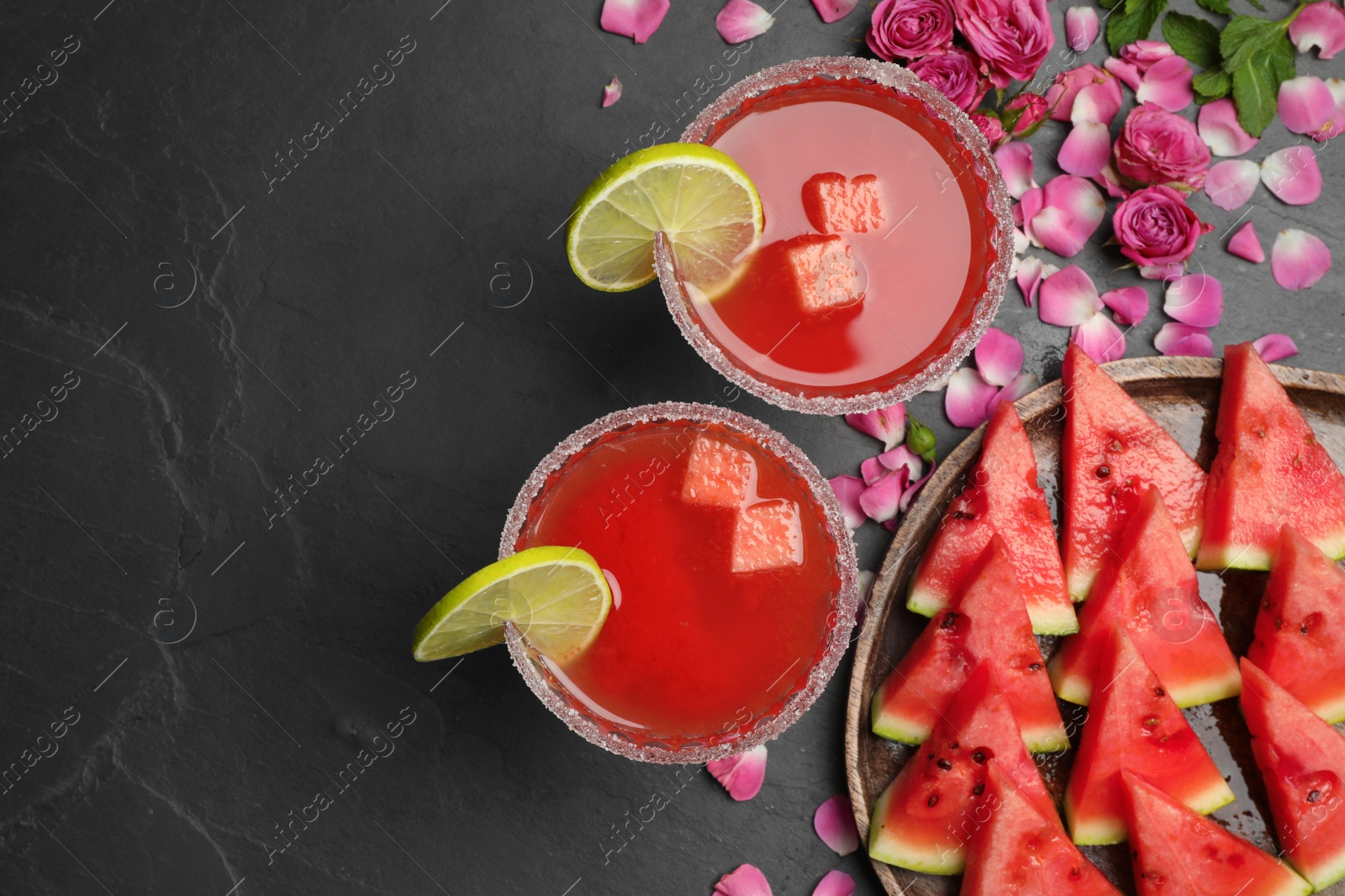 Photo of Flat lay composition with fresh watermelon juice and rose petals on black table. Space for text