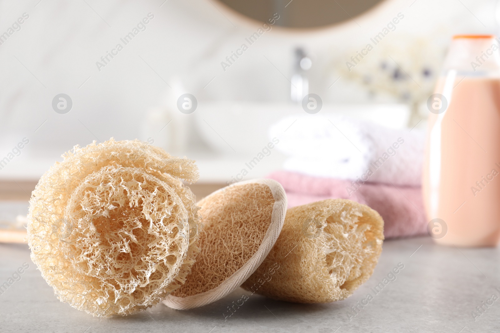 Photo of Natural loofah sponges on table in bathroom. Space for text