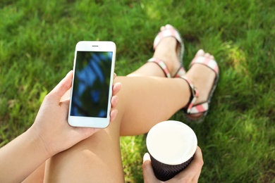 Woman using smartphone with blank screen outdoors, closeup. Mock up for design