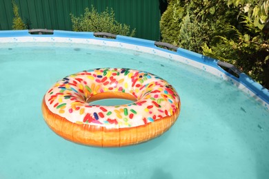 Photo of Inflatable ring floating on water in above ground swimming pool outdoors