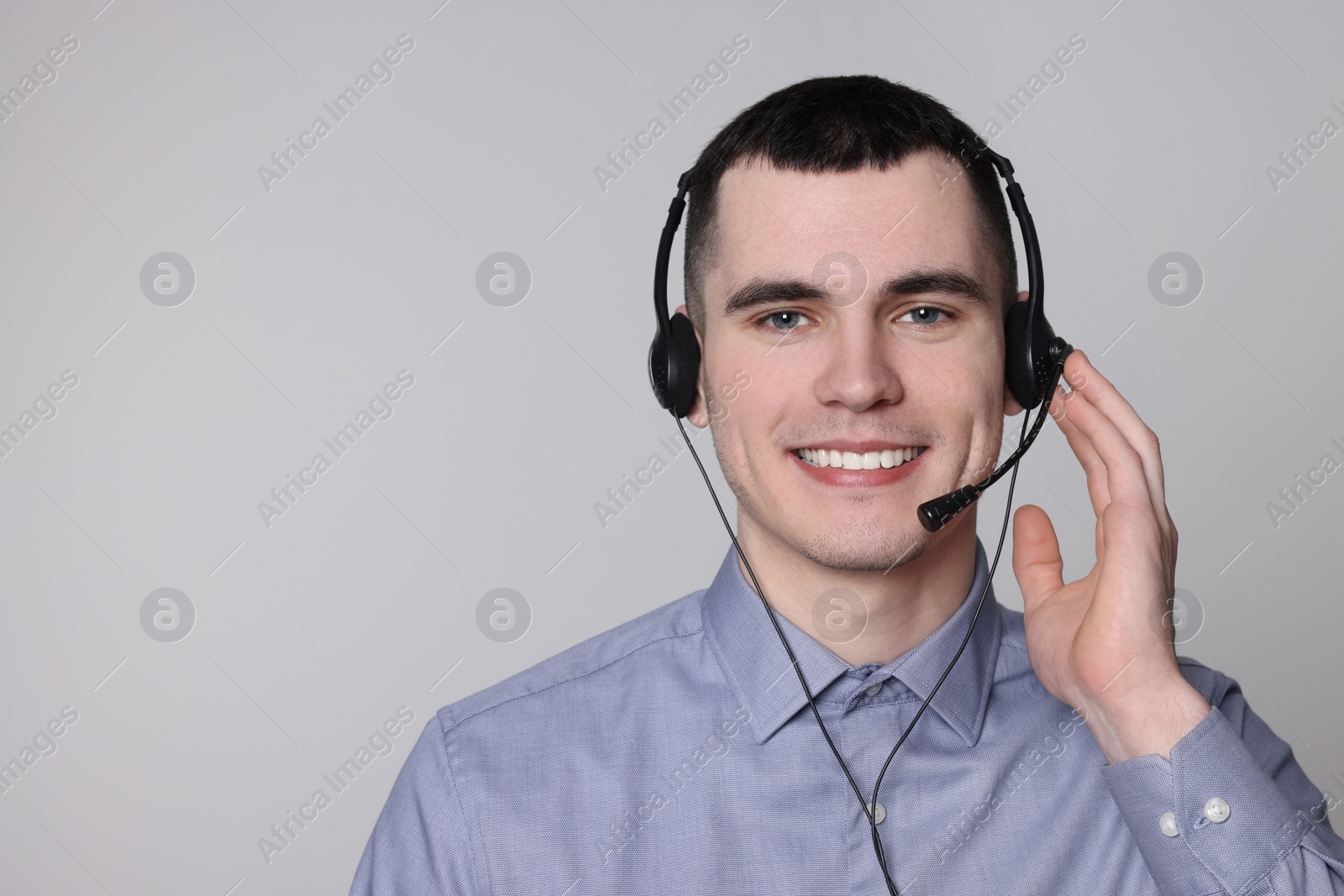 Photo of Hotline operator with headset on light grey background, space for text