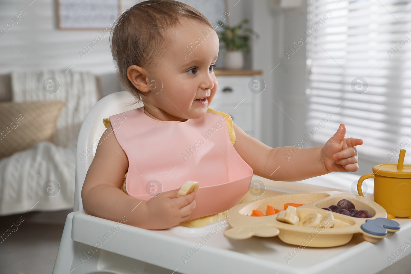 Photo of Cute little baby wearing bib while eating at home