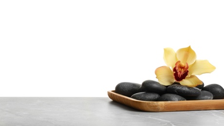 Photo of Wooden plate with orchid flower and spa stones on table against white background. Space for text