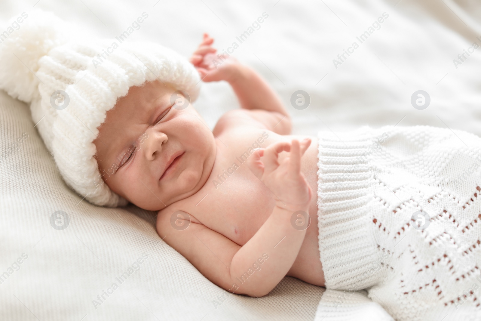 Photo of Adorable newborn baby in warm hat lying on bed