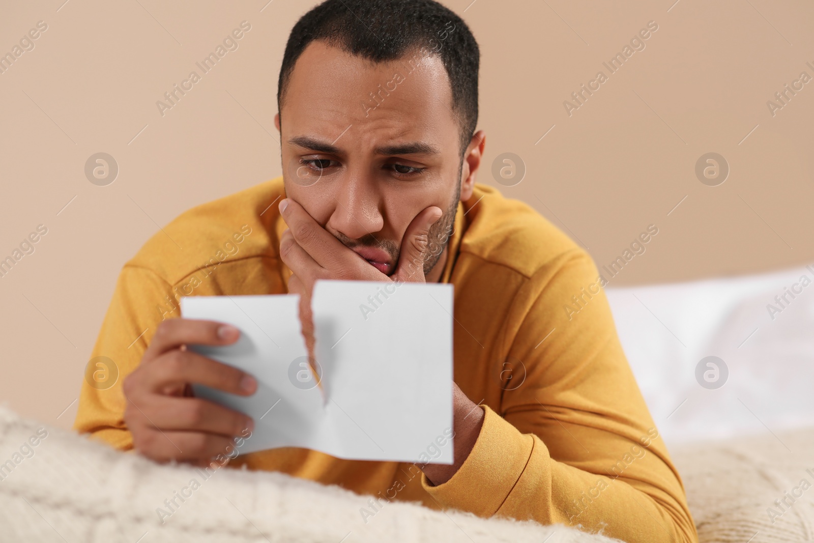 Photo of Upset African American man with torn photo indoors. Divorce concept