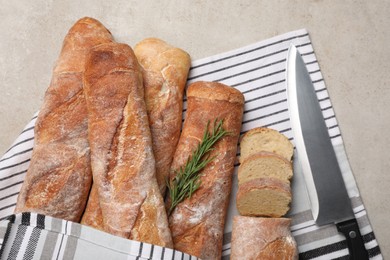 Photo of Fresh crispy baguettes and knife on grey table, top view