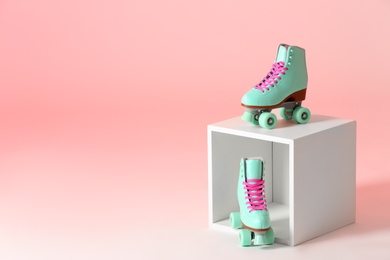 Pair of vintage roller skates and storage cube on color background. Space for text