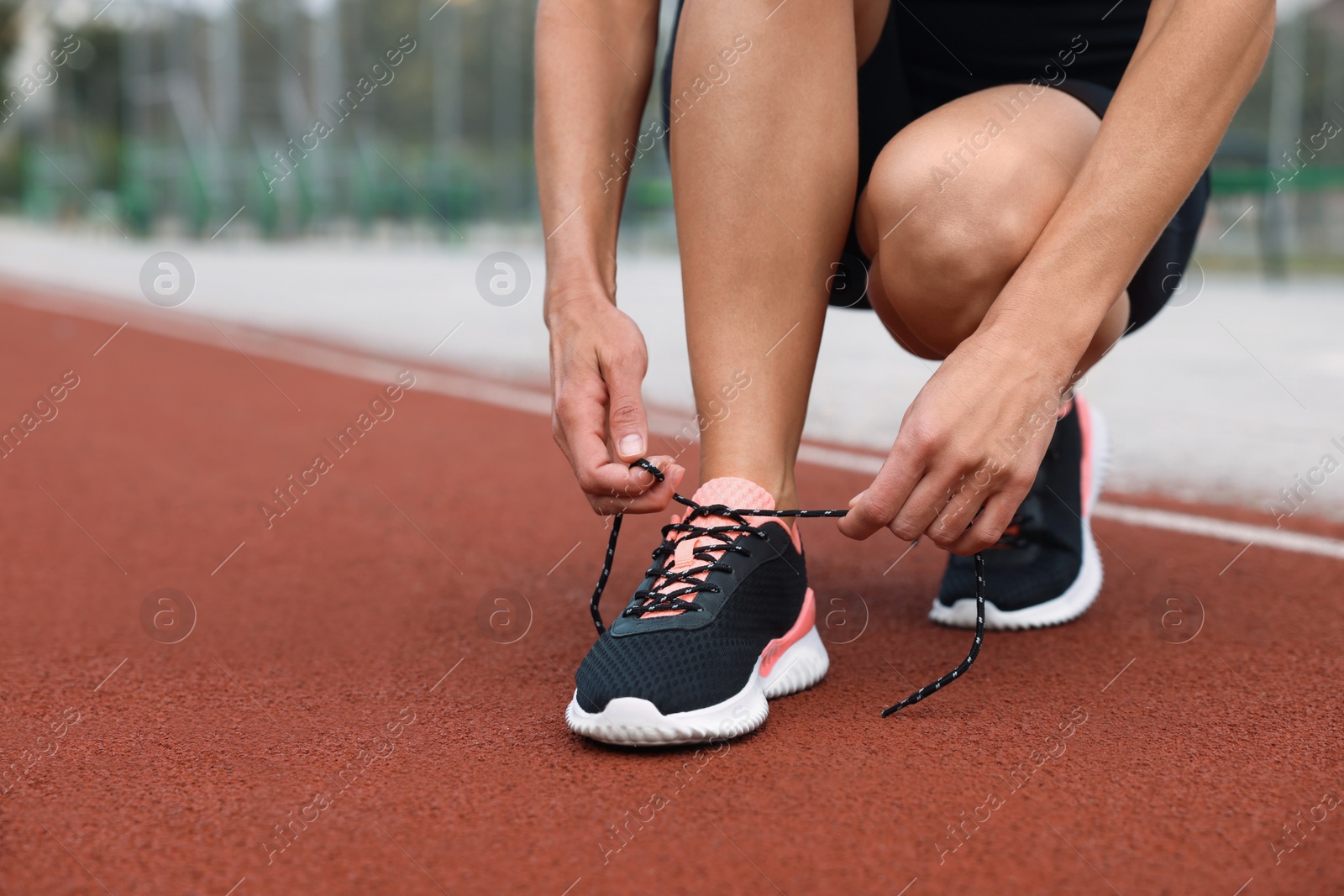 Photo of Woman tying shoelaces before training outdoors. closeup. Space for text